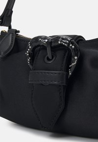 Svart nylonhandväska med texturerad yta, som har ett glänsande svart spänne accentuerat med små klara kristaller, samt en läderrem.