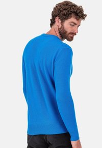 Blauer Strickpullover mit langen Ärmeln und rundem Halsausschnitt. Die Textur wirkt weich und leicht dehnbar. Gerippter Saum und Bündchen.