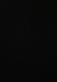 Svart textiltyg med en slät, matt yta och subtil elastisk känsla. Har en horisontell söm över mitten.