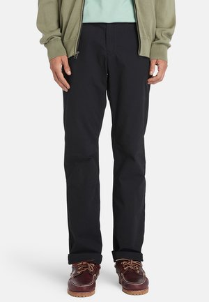 Heren marineblauwe chinos met een slim fit. Gemaakt van katoen, met een gladde textuur, voorzakken en opgerolde mouwen. In combinatie met bruinouwe boot schoenen.