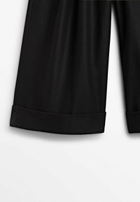 Zwarte op maat gemaakte broek met een gladde textuur, omgeslagen hemden en een rechtartige pasvorm. De stof lijkt lichtgewicht en kreukvrij te zijn.