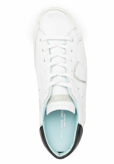 Scarpa da ginnastica bianca in pelle con tallone nero, lacci piatti, soletta azzurro chiaro e dettagli testurizzati. Superficie liscia con dettagli perforati sui lati.