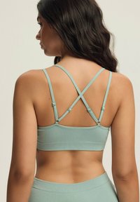 Jasnoniebieski prążkowany stanik braletka z regulowanymi krzyżującymi się ramiączkami i bezszwowym pasem pod biustem. Wygodny materiał i minimalistyczny design.