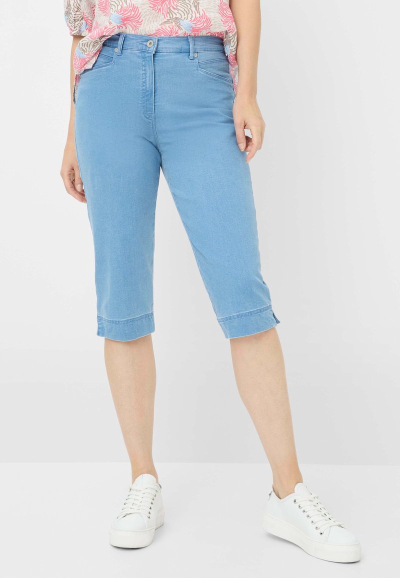Pantaloni capri in denim azzurro chiaro con taglio dritto, orlo arrotolato e tasche frontali, abbinati a sneaker bianche con lacci.