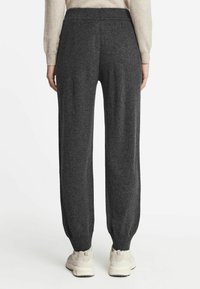 Koksgrå sweatpants med en tapered design, elastisk talje og ribbede manchetter. Satylet med lyse farvede sportssko.
