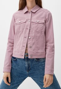 Chaqueta de mezclilla rosa con cuello, dos bolsillos frontales y botones plateados. Tejido texturizado, diseño ajustado y longitud corta combinada con jeans azules.