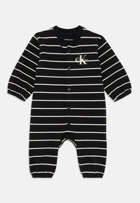Čierno-bielo pruhovaný bavlnený overal s dlhými rukávmi, patentkami na prednej strane a elastickými manžetami. Logo Calvin Klein na hrudi.