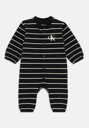 Μαύρη και λευκή ριγέ βαμβακερή φόρμα με μακριά μανίκια, κουμπιά σνάπ κατά μήκος του μπροστινού μέρους και ελαστικούς καρπούς. Λογότυπο Calvin Klein στο στήθος.