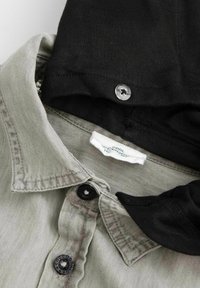 Szary koszula z guzikami z czarnym kapturem. Posiada czarne guziki oraz widoczny metkę przy szyi. Miękka tekstura z casualowym stylem.