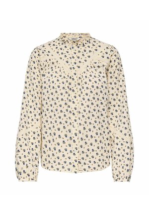 Krémová blúzka s dlhým rukávom, malým modrým kvetinovým vzorom, detailmi s čipkou, zapínaním na gombíky vpredu a mierne riaseným záševkom.