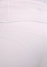 Φως ροζ ριμπ ύφασμα με ορατές ραφές σε εφαρμοστή ένδυση, με μικρό ανάγλυφο λογότυπο κοντά στην περιοχή του ώμου.