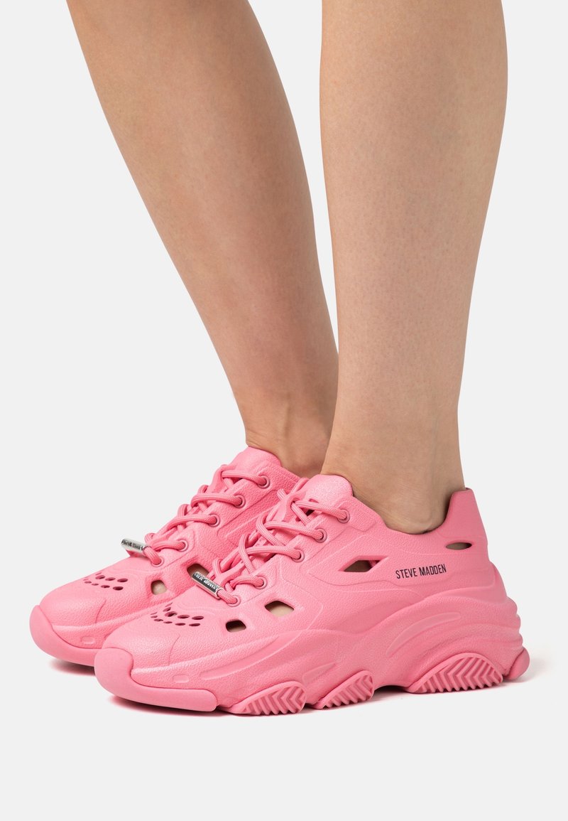 Sneaker rosa con finitura testurizzata, design con lacci e fori di ventilazione. Presenta una suola spessa e pronunciata con grip. Marchio "STEVE MADDEN".