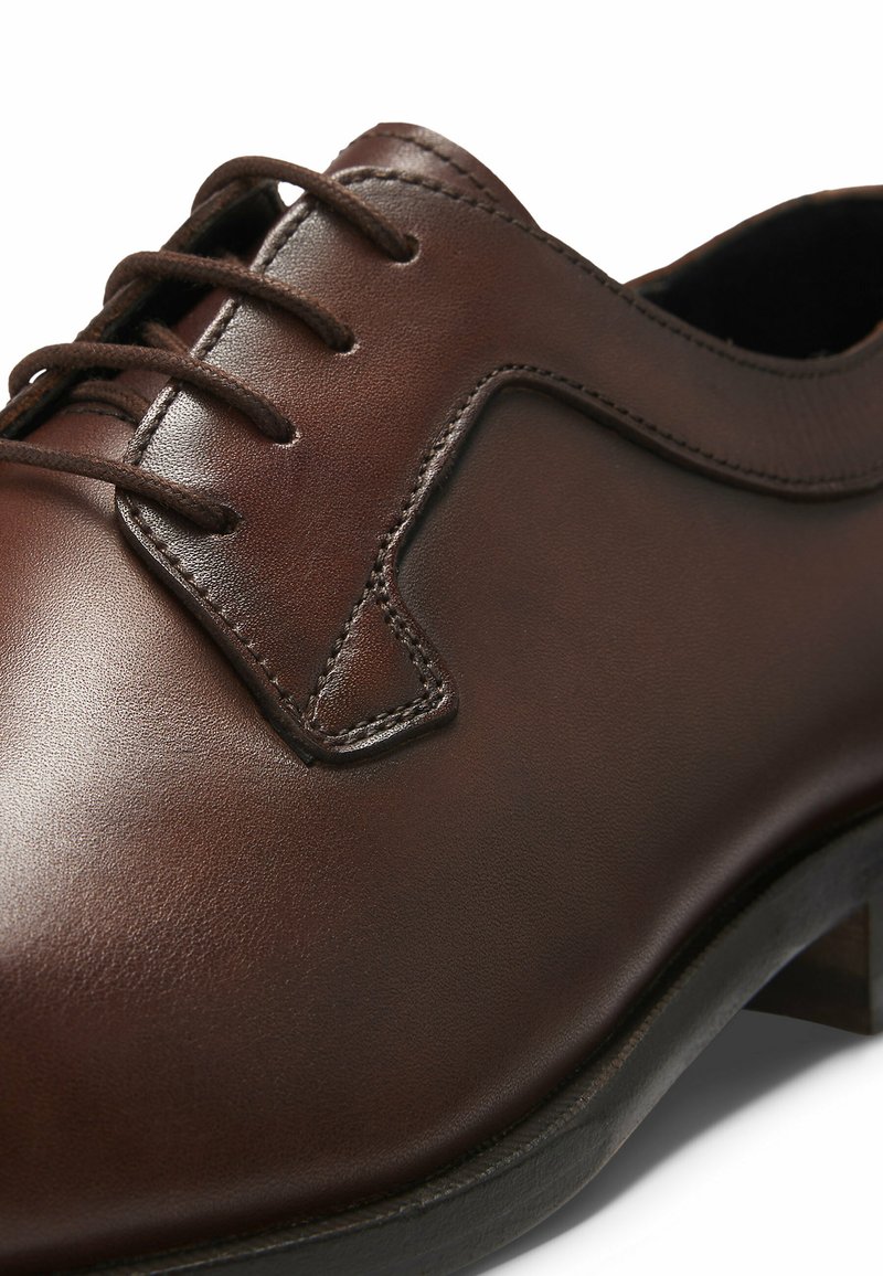 Chaussure habillée en cuir marron avec une finition lisse, un bout rond, des détails de surpiqûres surélevées et un design classique à lacets avec des lacets assortis.