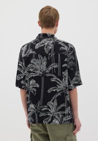 Korte mouwen zwart shirt met wit palmboom patroon, lichtgewicht stof, relaxte pasvorm, open kraag en rugpas detail.