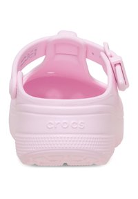 Różowe Crocsy z zamkniętym tyłem, regulowanym paskiem na pięcie i teksturowaną podeszwą. Logo na boku, gładki materiał o matowym wykończeniu.