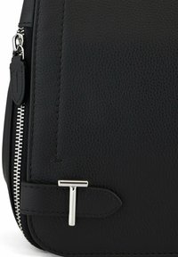 Schwarze Lederhandtasche mit strukturiertem Finish, ausgestattet mit silbernen Reißverschlussbeschlägen und einem markanten silbernen T-förmigen Akzent auf der Vorderseite.
