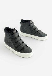 Sneakers alte nere con superficie testurizzata, dotate di tre cinturini in velcro e un interno morbido e peloso. Suola in gomma bianca.