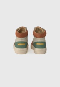 Baskets montantes offrant un mélange de cuir vert clair, de daim marron et d'accents jaunes sur une semelle en caoutchouc beige.