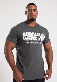 Graues Baumwoll-T-Shirt mit "GORILLA WEAR" und "UNITED STATES OF AMERICA" in fettem weißen Text. Kurze Ärmel, normale Passform.