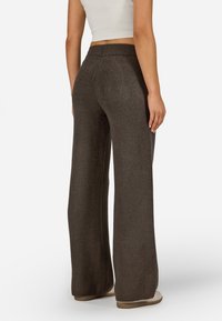 Široké tmavočokoládové pletené nohavice so pružným pásom. Materiál sa zdá byť mäkký s jemne textúrovaným povrchom.