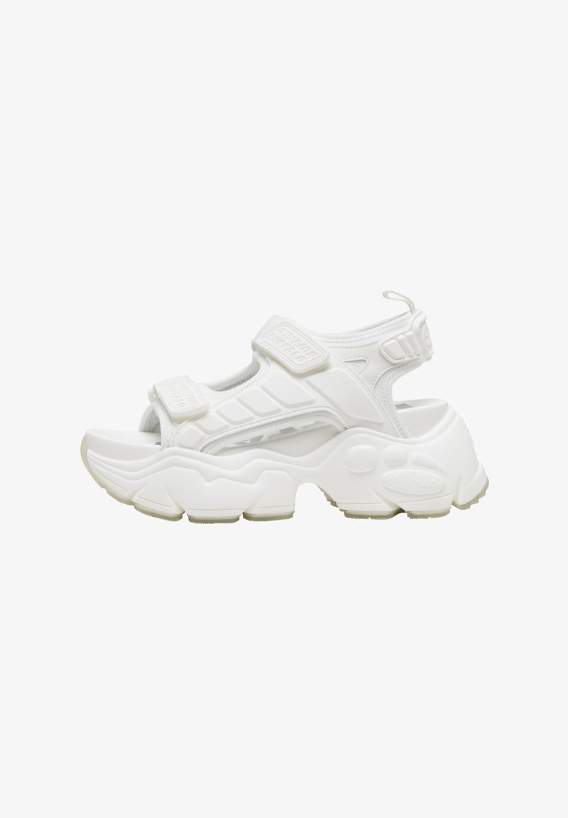 Sandale sportive blanche avec brides en Velcro réglables, semelle rembourrée, design ouvert, profil épais et accents texturés. Matière synthétique légère.