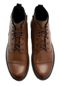Brązowe skórzane botki za kostkę z okrągłym noskiem, sznurowanym przodem i kontrastującą czarną gumową podeszwą. Posiadają detale w postaci przeszyć i gładką teksturę.