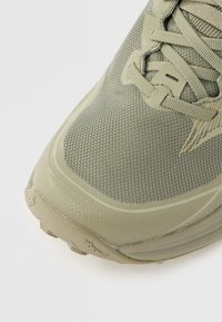 Chaussure de course légère en mesh vert clair. Dispose d'une tige texturée, d'un embout renforcé et d'une semelle à motifs pour une meilleure adhérence.