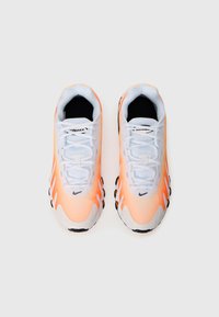 Tenisky s prechodom farieb z oranžovej do bielej, sieťovaný zvršok, čierna vnútorná podšívka a štruktúrovaná podrážka s viditeľnými vzduchovými vankúšikmi.