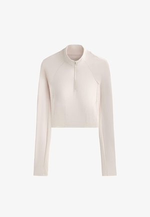 Long-sleeve, light beige cropped top with half-zip front and ribbed texture panels on sides and sleeves.