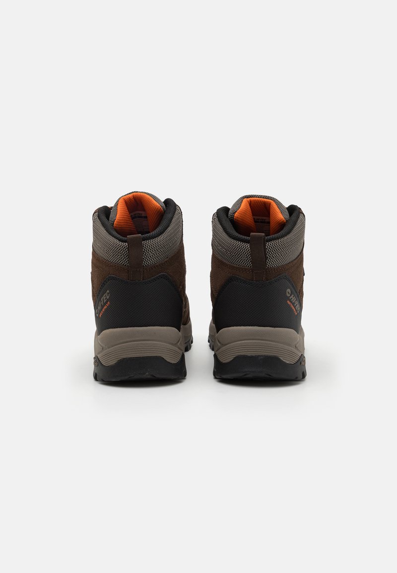 Scarpe da trekking marroni con tomaia testurizzata, tallone rinforzato, suola in gomma nera e accenti arancioni sul collo. Design robusto per uso all'aperto.