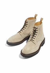 Botines de ante beige con detalles decorativos de brogue, cordones marrones, suela de goma duradera y lengüetas en el collar para un fácil calzado.