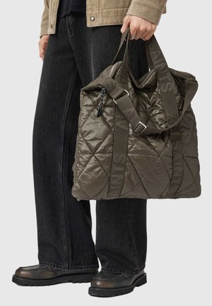 Bolsa tote de olivo acolchada, con cierre de cremallera, correas de tela dobles y acentos impresos de "SAINTS". La superficie texturizada añade detalle.