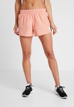 Lichtroze sportshorts met een elastische tailleband en een wit logo, gecombineerd met zwarte hardloopschoenen met witte zolen en accenten.