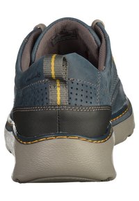 Scarpa in pelle blu con accenti grigi, cuciture gialle, suola testurizzata, dettagli perforati e un tassello sul retro per facilitarne l'uso.