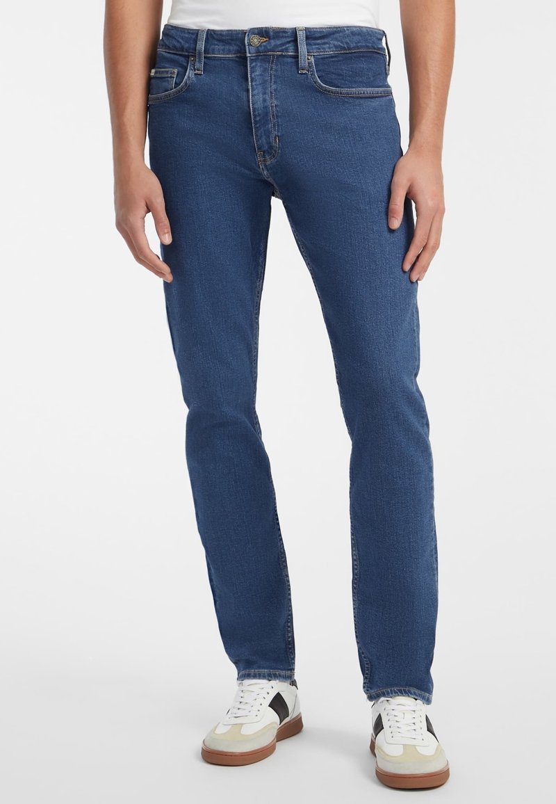Jeans en denim bleu foncé à coupe ajustée, avec un design classique à cinq poches, des passants pour ceinture et une texture délavée moyenne.