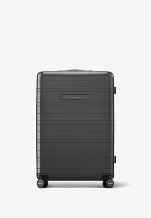 Schwarzer Hartschalenkoffer mit einem strukturierten Streifenmuster, einem Tragegriff oben und vier leise rollenden Rädern. Verfügt über einen Seitenverschluss.