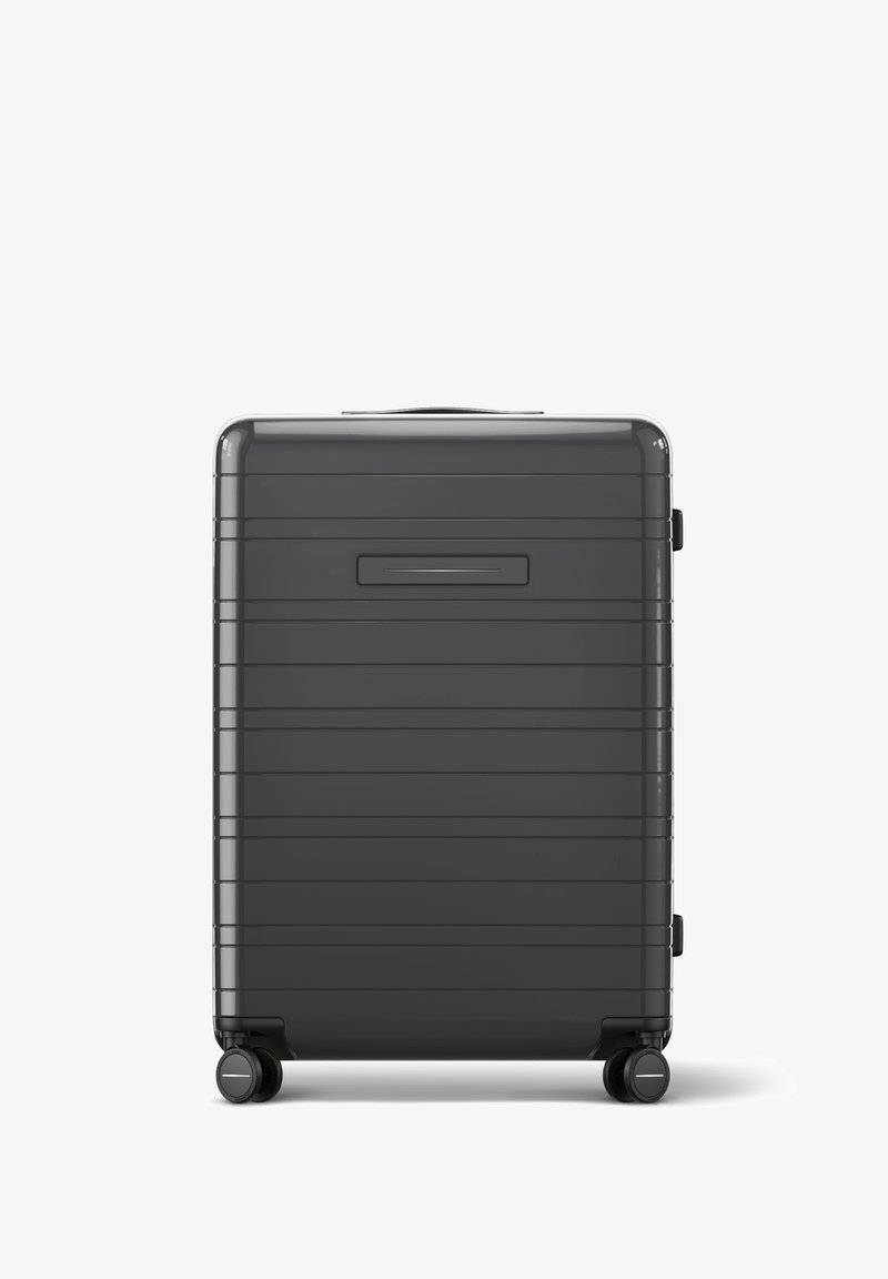 Schwarzer Hartschalenkoffer mit einem strukturierten Streifenmuster, einem Tragegriff oben und vier leise rollenden Rädern. Verfügt über einen Seitenverschluss.