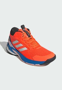 Bright orange athletic shoe with silver accents and black details. Mesh upper with textured fabric and a blue rubber sole. Lightweight design.