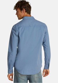 Camicia a maniche lunghe azzurro chiaro con colletto button-down, piega posteriore singola e polsini con bottone. Tessuto di cotone morbido, design con orlo curvo.