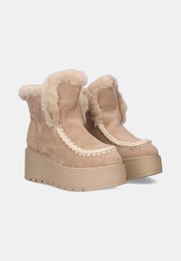 Botas de plataforma beige hechas de ante con un borde de piel de peluche, con un diseño de costuras crema decorativas en la parte delantera y suelas de goma texturizadas.