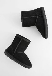 Schwarze Wildleder-F ankle boots mit weicher Innenausstattung, runder Zehenpartie, flacher Gummisohle und kontrastierenden Nähten entlang der Nähte.