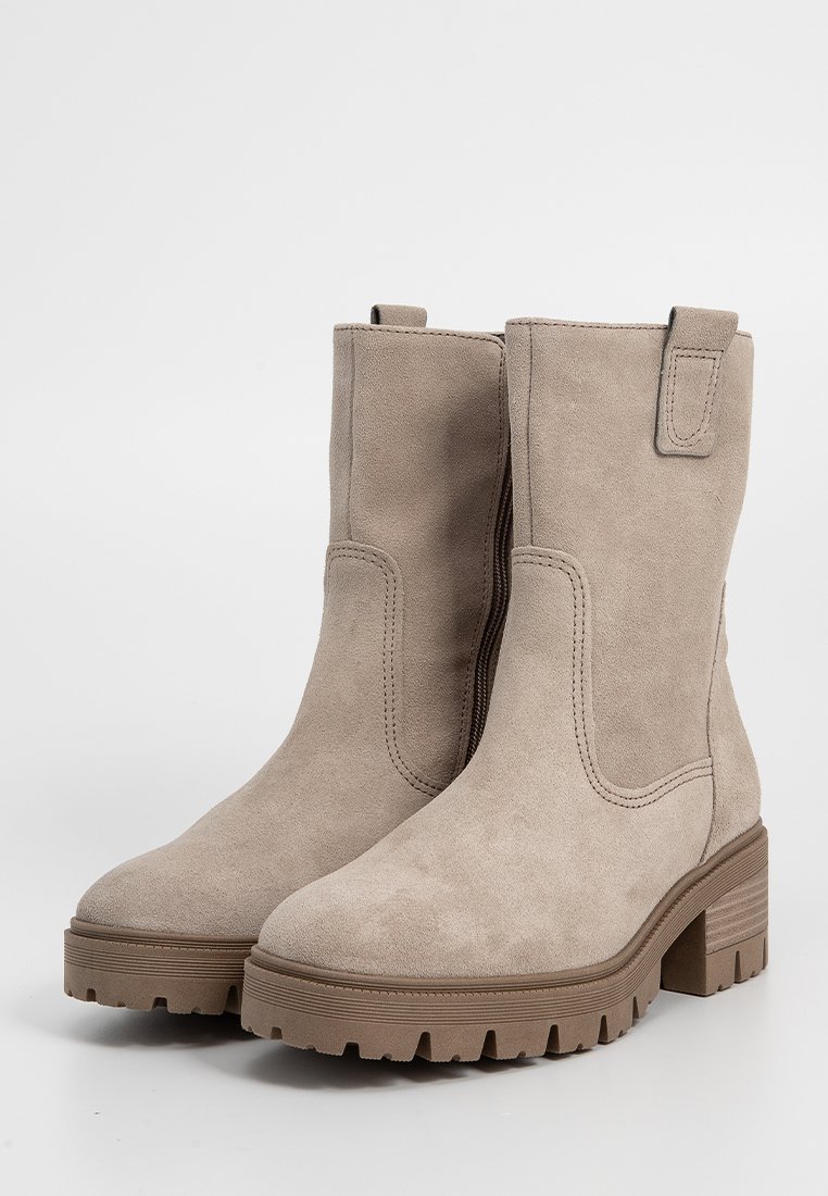 Beżowe zamszowe botki za kostkę z grubą gumową podeszwą, bocznymi elastycznymi panelami i pętlami do zakładania, z płaskim obcasem i teksturowaną powierzchnią.