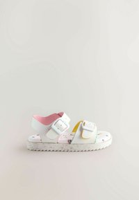 Witte sandalen met twee verstelbare banden, een roze binnenvoering en een gestructureerde, gemusterde zool met kleurrijke illustraties.
