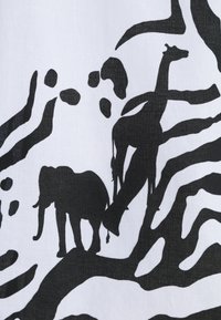 Black silhouette patterns of an elephant and giraffe on a white fabric background, featuring an abstract design with organic shapes.
