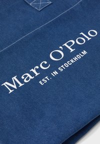 Blauer Baumwollcanvas-Stoff mit weißem Aufdruck "Marc O'Polo EST. IN STOCKHOLM" und kontrastierenden Nähten. Verfügt über eine rechteckige Form.