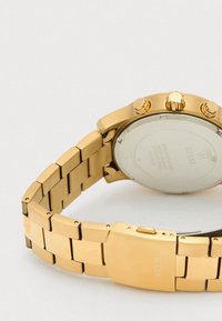 Relógio de pulso em metal dourado com bracelete em elos, três botões laterais e verso em aço inoxidável gravado com a marca e detalhes de resistência à água.