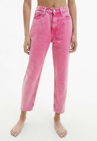 Jeans de mezclilla de tiro alto en color rosa, con un corte relajado, que presentan un cierre de botón, bolsillos frontales y una textura desvanecida.