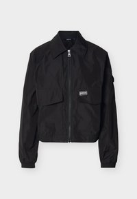 Μαύρο ελαφρύ μπουφάν με φερμουάρ, φαρδύ γιακά, δύο εμπρόσθιες τσέπες με καπάκι, ελαστικά μανίκια και μικρό λογότυπο μάρκας στην δεξιά τσέπη.