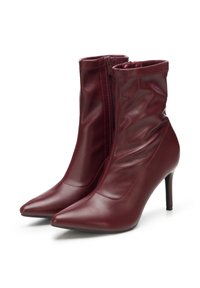 Pár bordó kožených kotníkových bot s špičatými špičkami, bočními zipy a jehlovými podpatky na bílém pozadí.