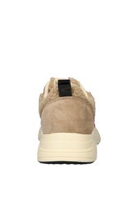 Beige sneaker with a soft suede and fur texture, featuring a black heel tab and a thick, creamy midsole. Classic athletic design.